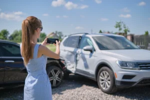 A snapshot of a person photographing an accident scene and damaged vehicle, illustrating essential steps to take after an accident